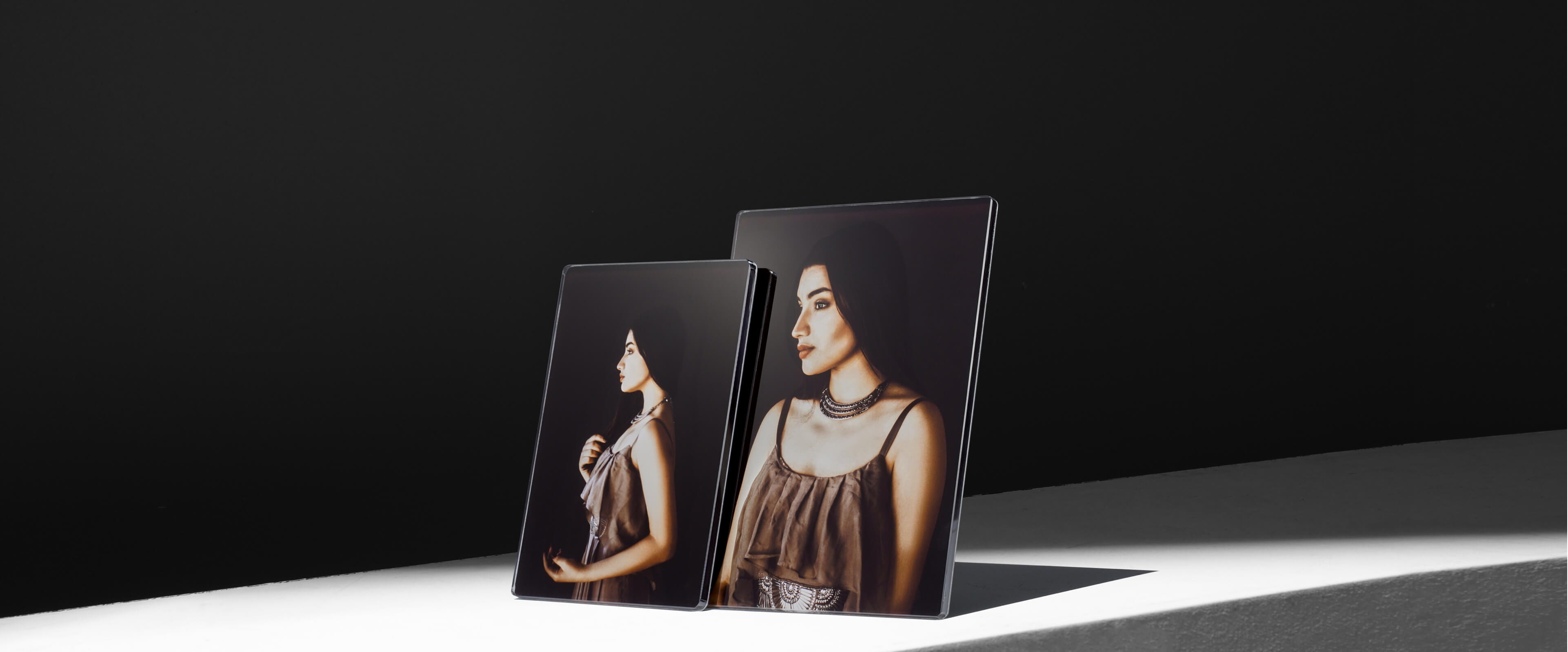 two acrylic photo plaques standing on a white table showing a woman in dress