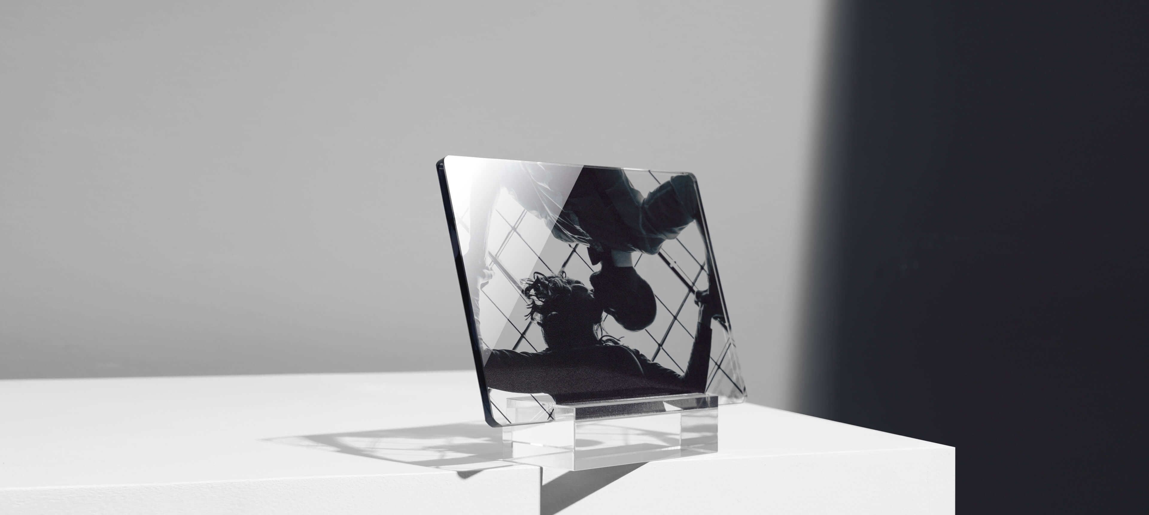 an acrylic photo stand on white table showing a couple kissing