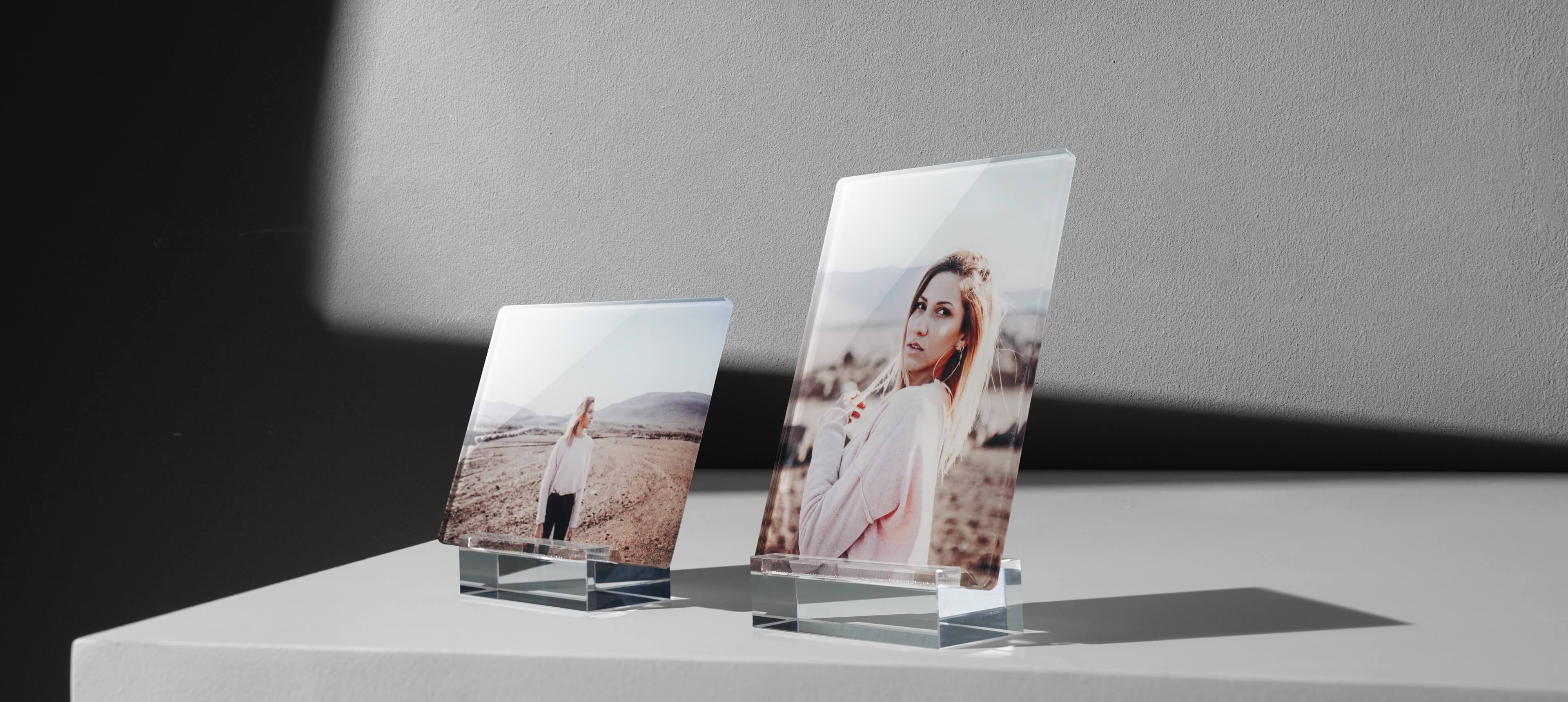 two acrylic photo stands on white table in different orientation showing a woman in pink sweater