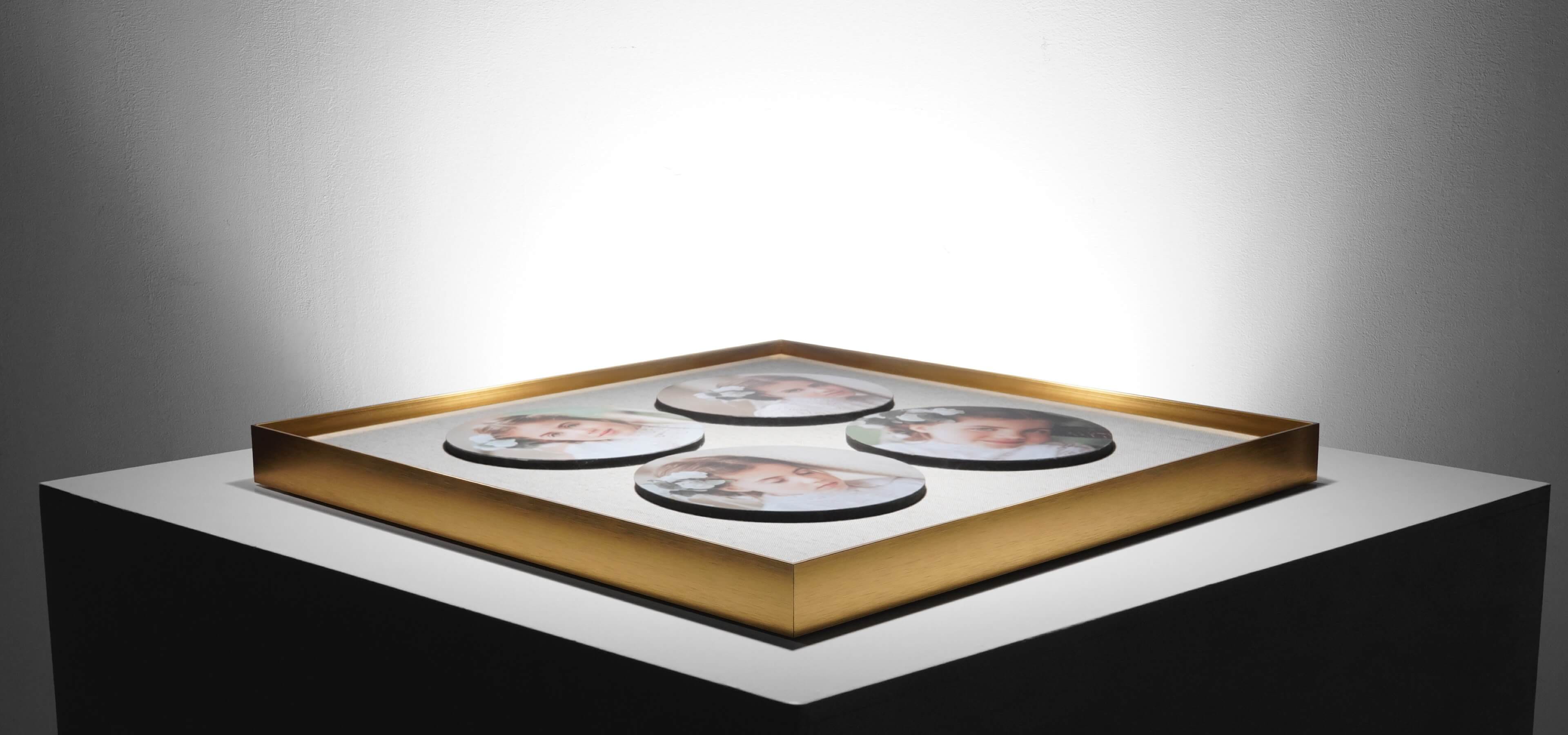 collage frame with thin gold frame and four circular photos laying on table