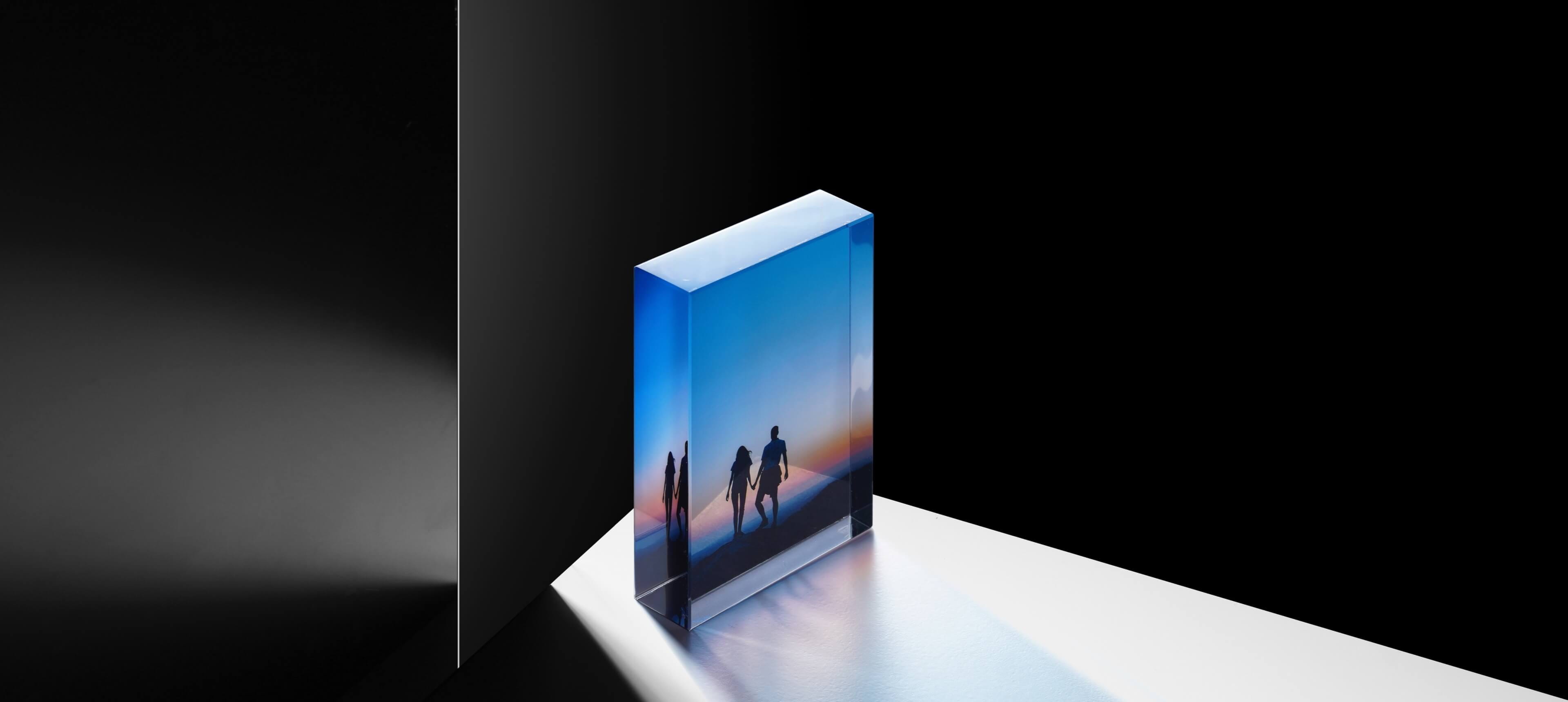 a crystal glass photo block stands on white table showing a couple at sunset