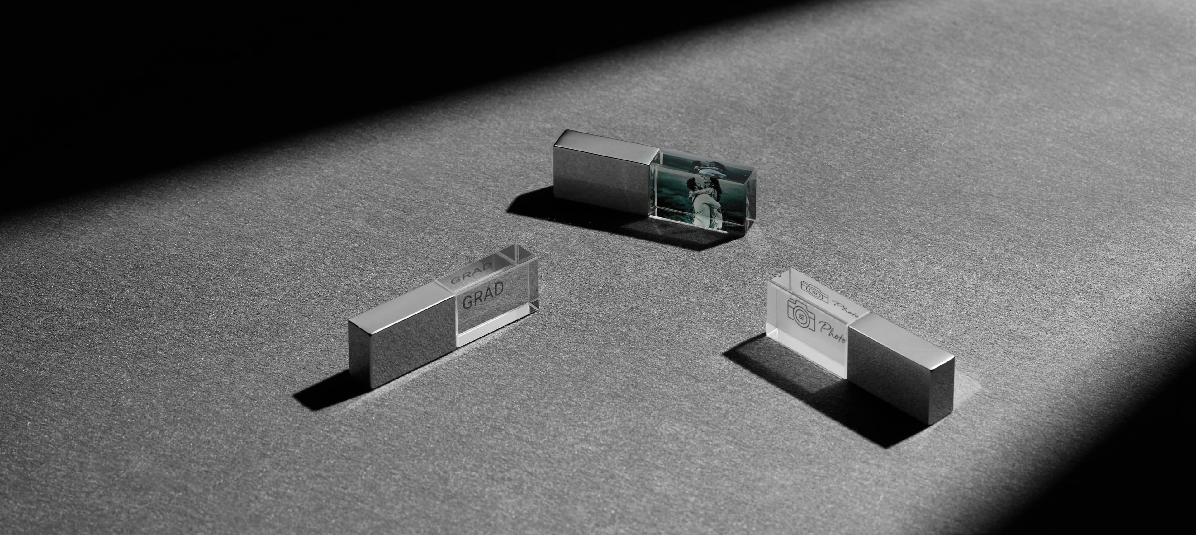 three crystal usb drives in different printing options on a grey table