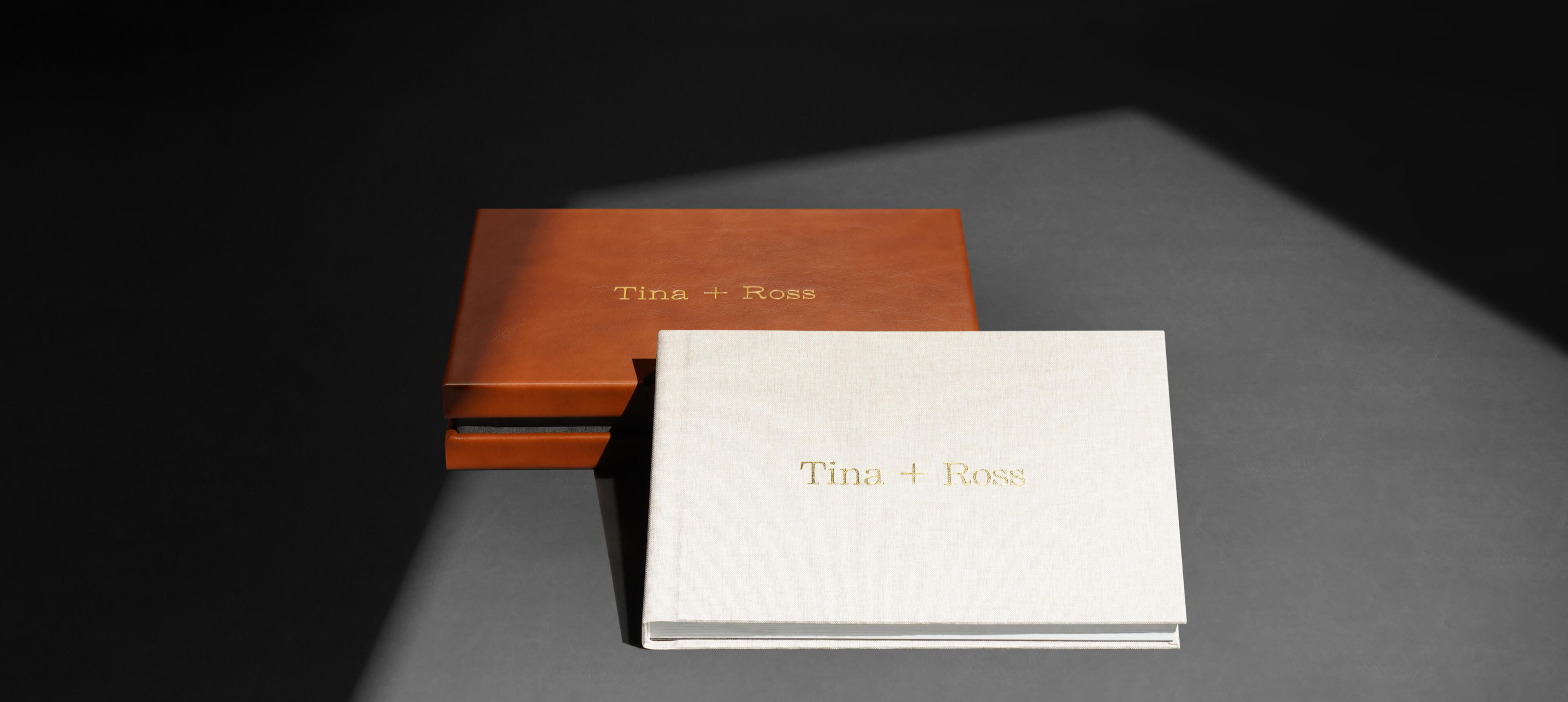 a design box album set showing showing a linen photo album leaning against a leather box