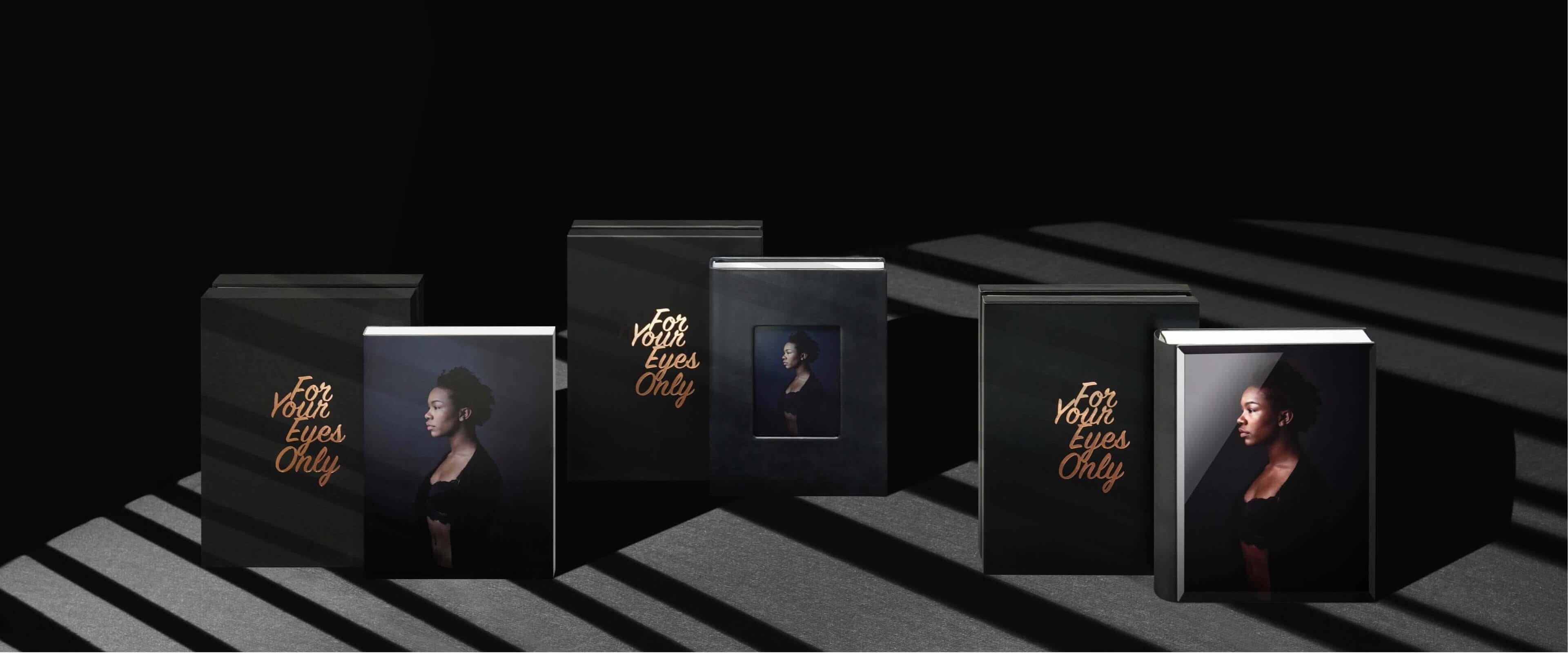 three black design boxes with albums showing woman in lingerie