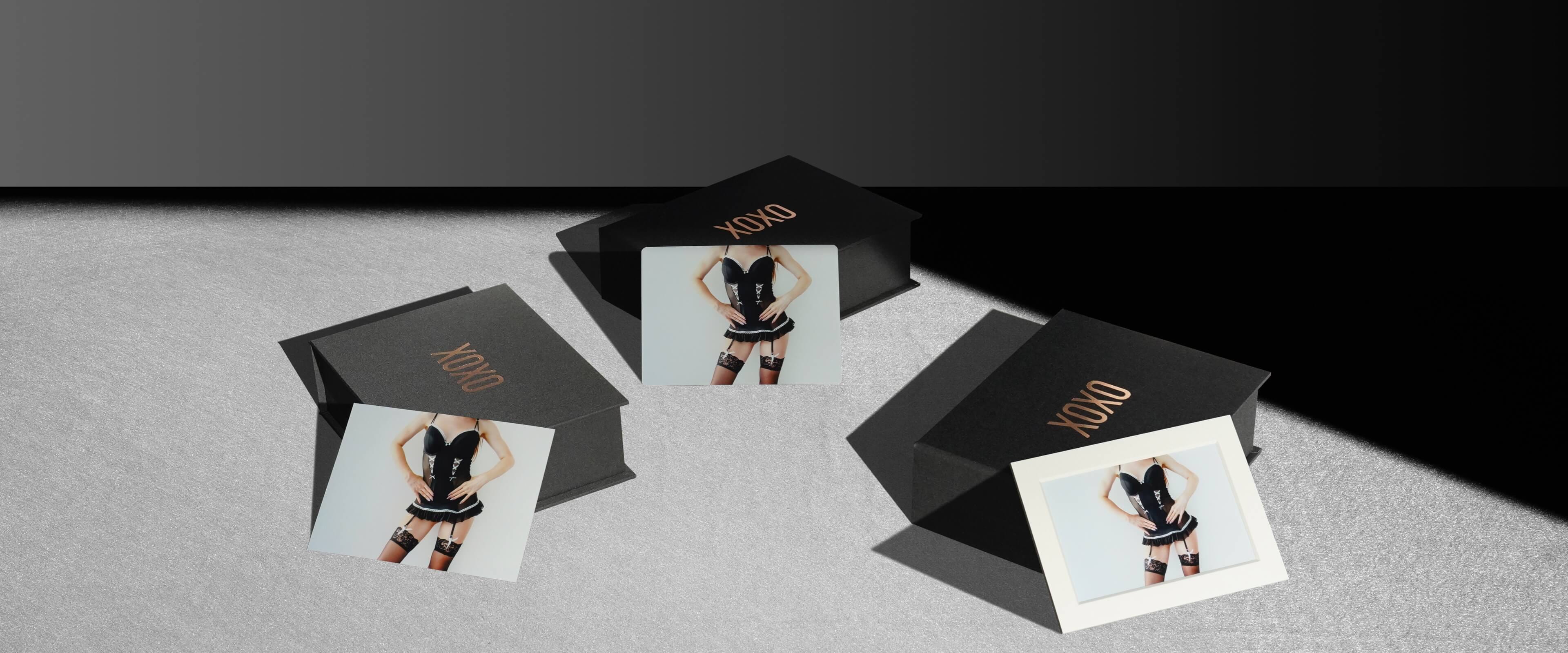 three black folio boxes with boudoir prints of woman in black lingerie