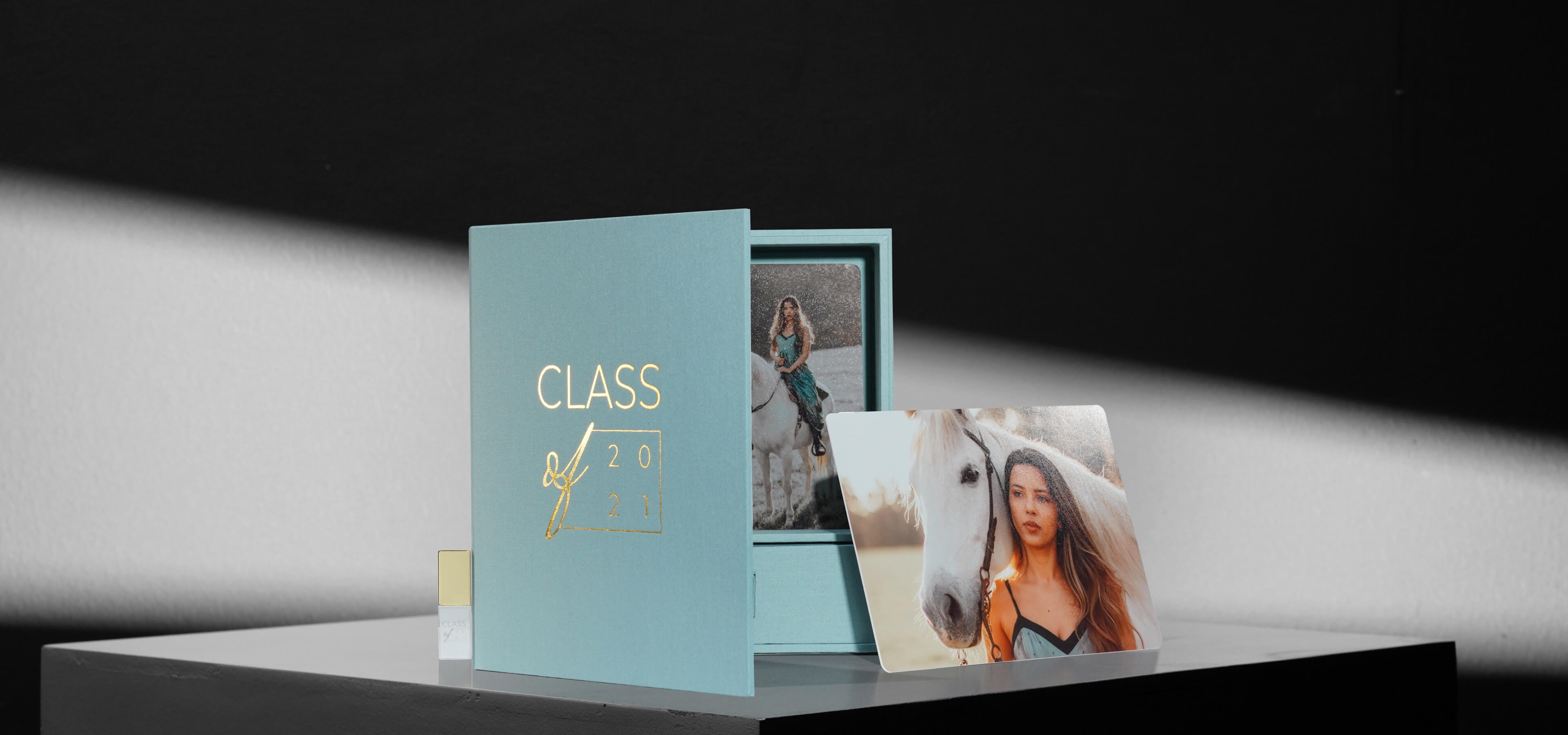 a folio box set showing a photo print and gold crystal usb next to a teal linen folio box
