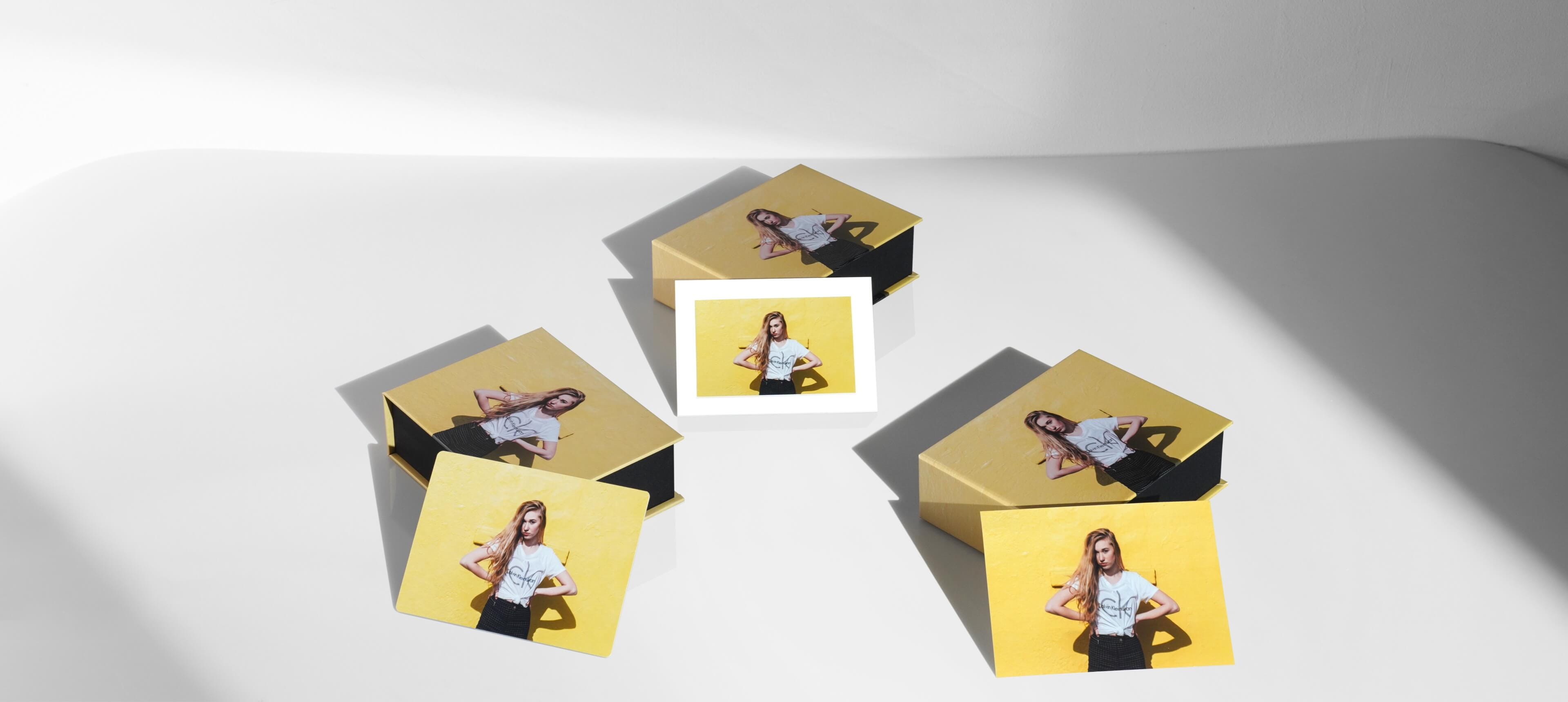 three image boxes with prints leaning against them showing girl on yellow background