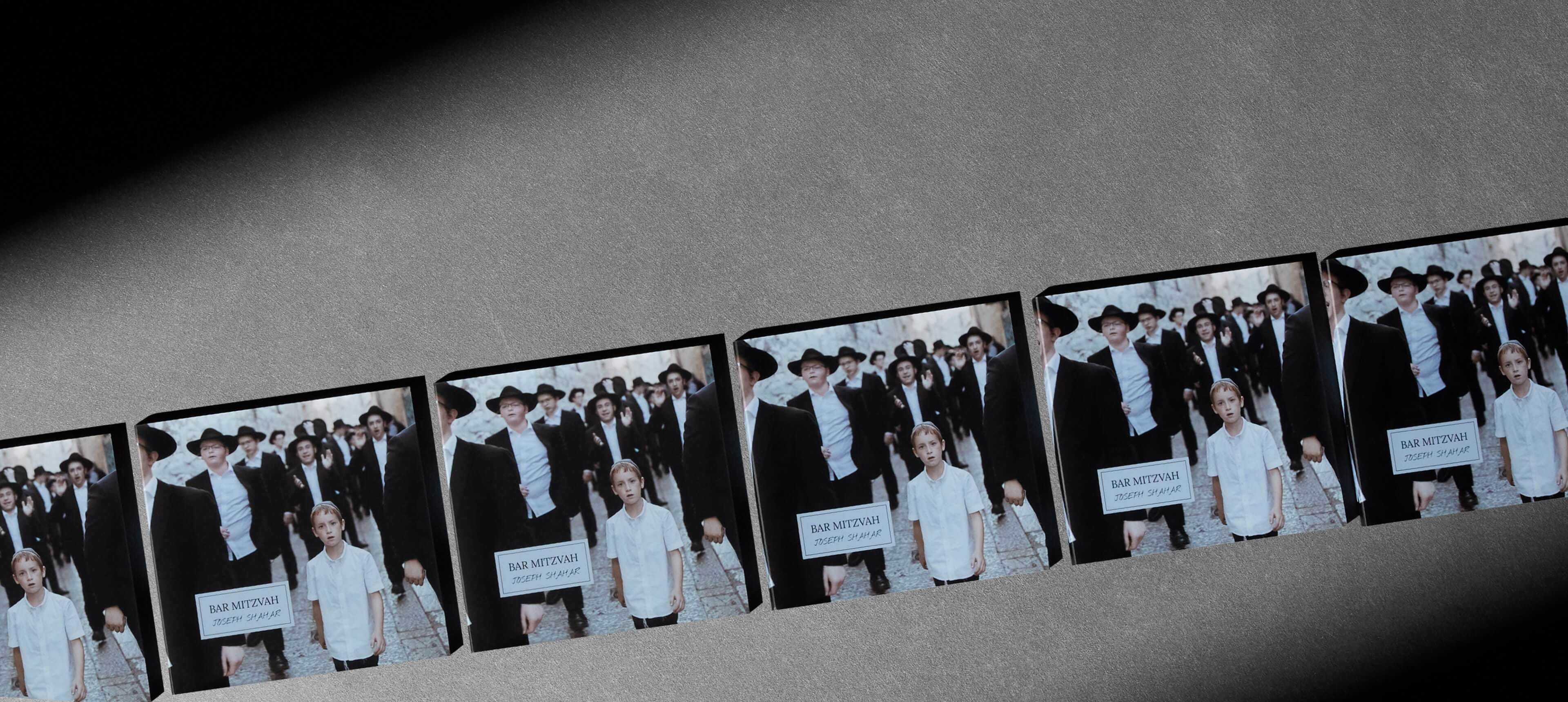 six layflat booklets on a grey table showing a crowd of orthodox jews in israel