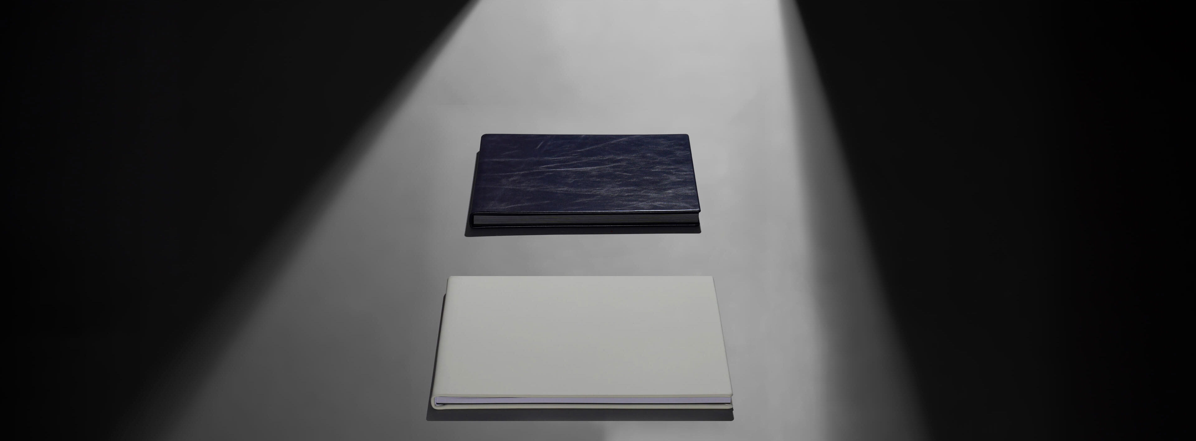 a white layflat photo book sitting next to a black flush mount album