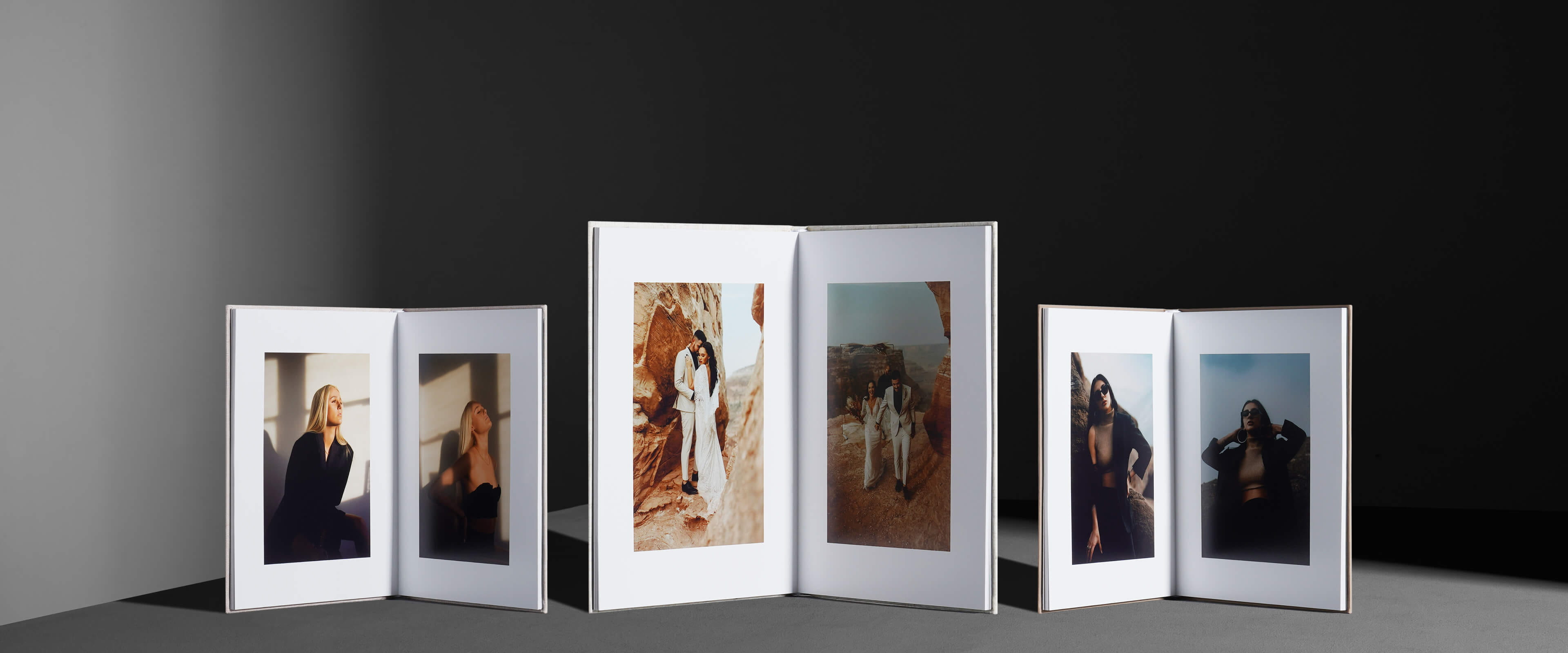three layflat photo books that are standing up with their pages opened