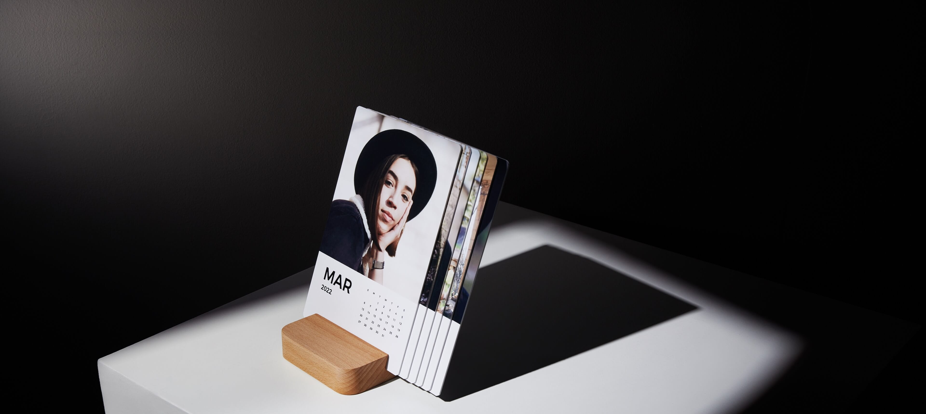 a little moments calendar on a white table showing a woman wearing a black hat