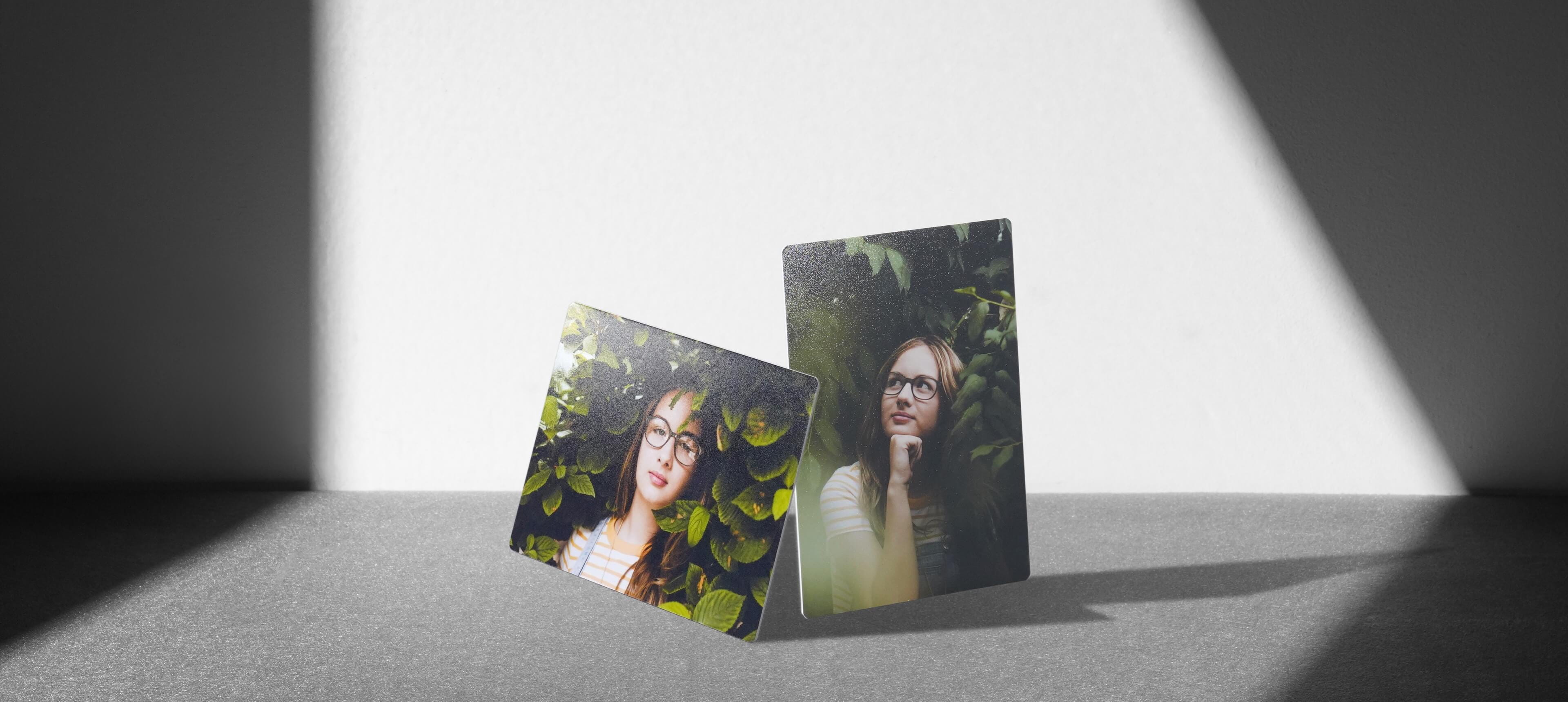 two prints lean on each other on grey table showing a woman in front of vegetation