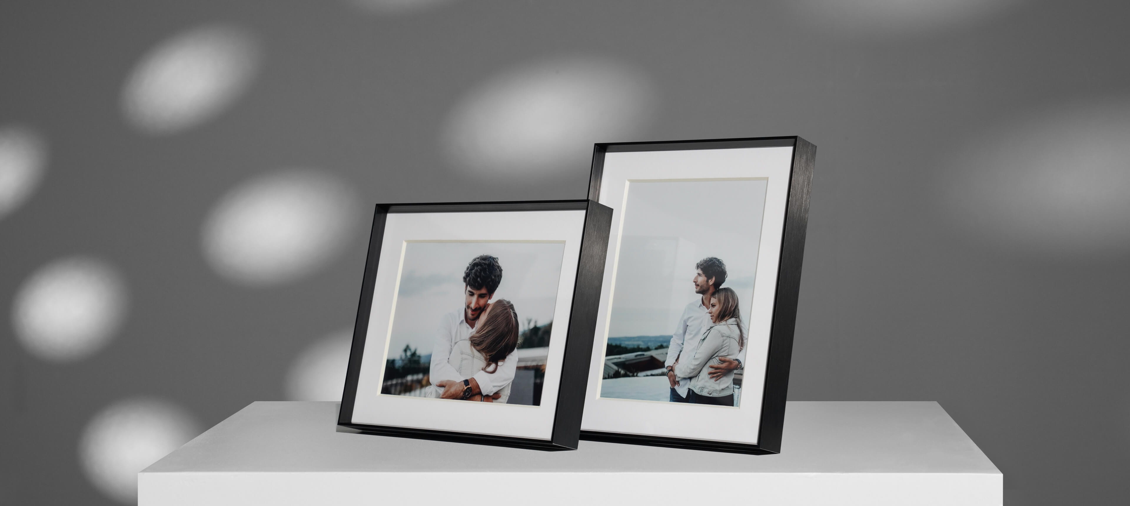 two framed tabletop metal prints on a white table showing a couple embracing