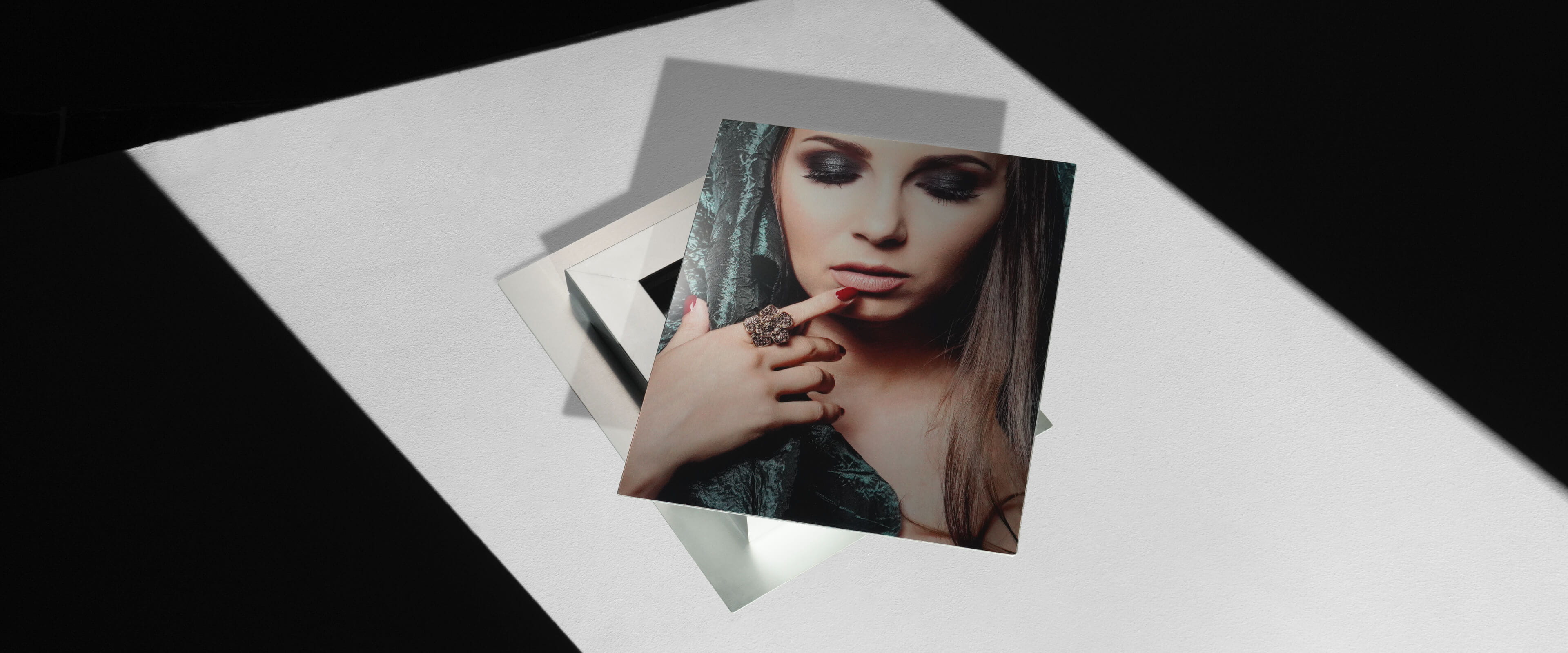 metal print stacked on top of another metal print showing a woman pointing finger at her face