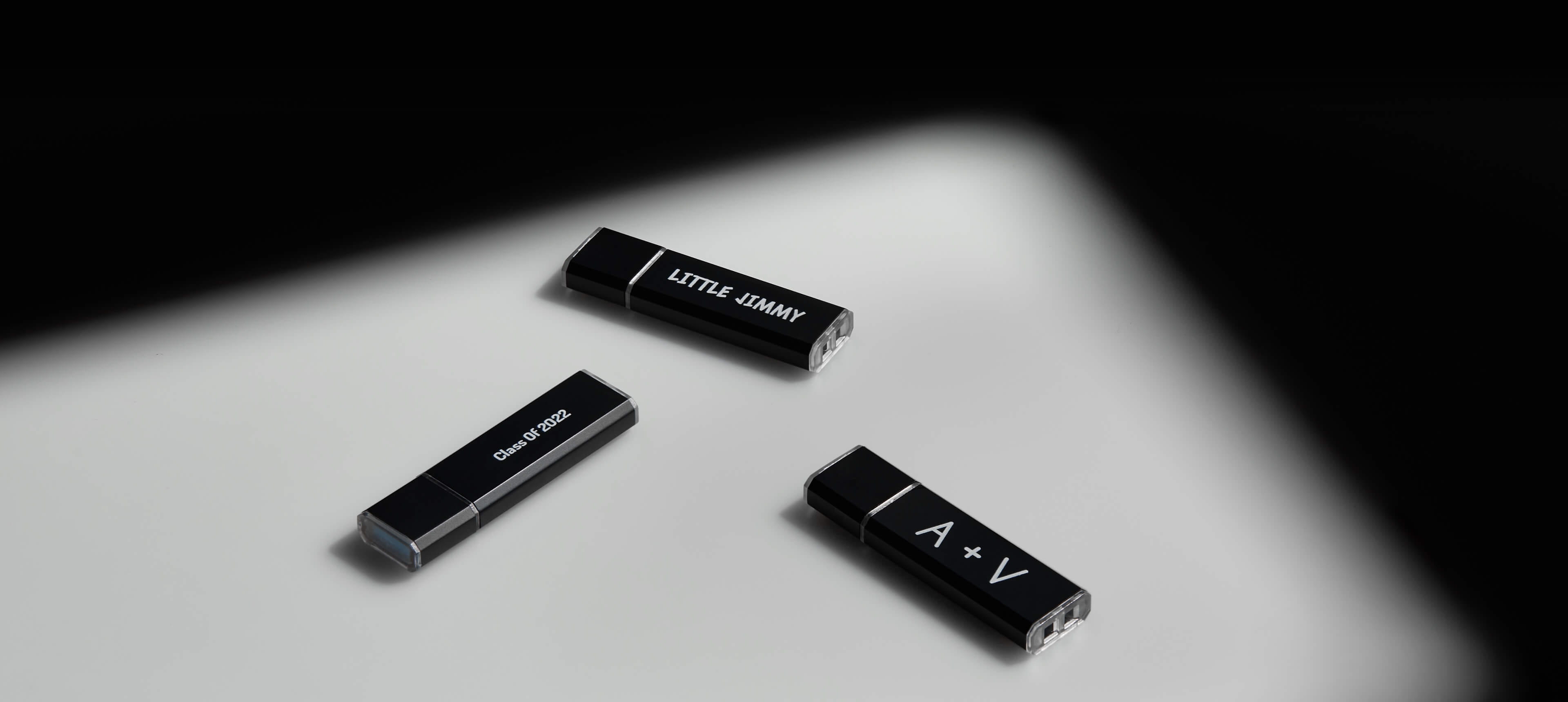 three metal usb drives with different printed text on a white table