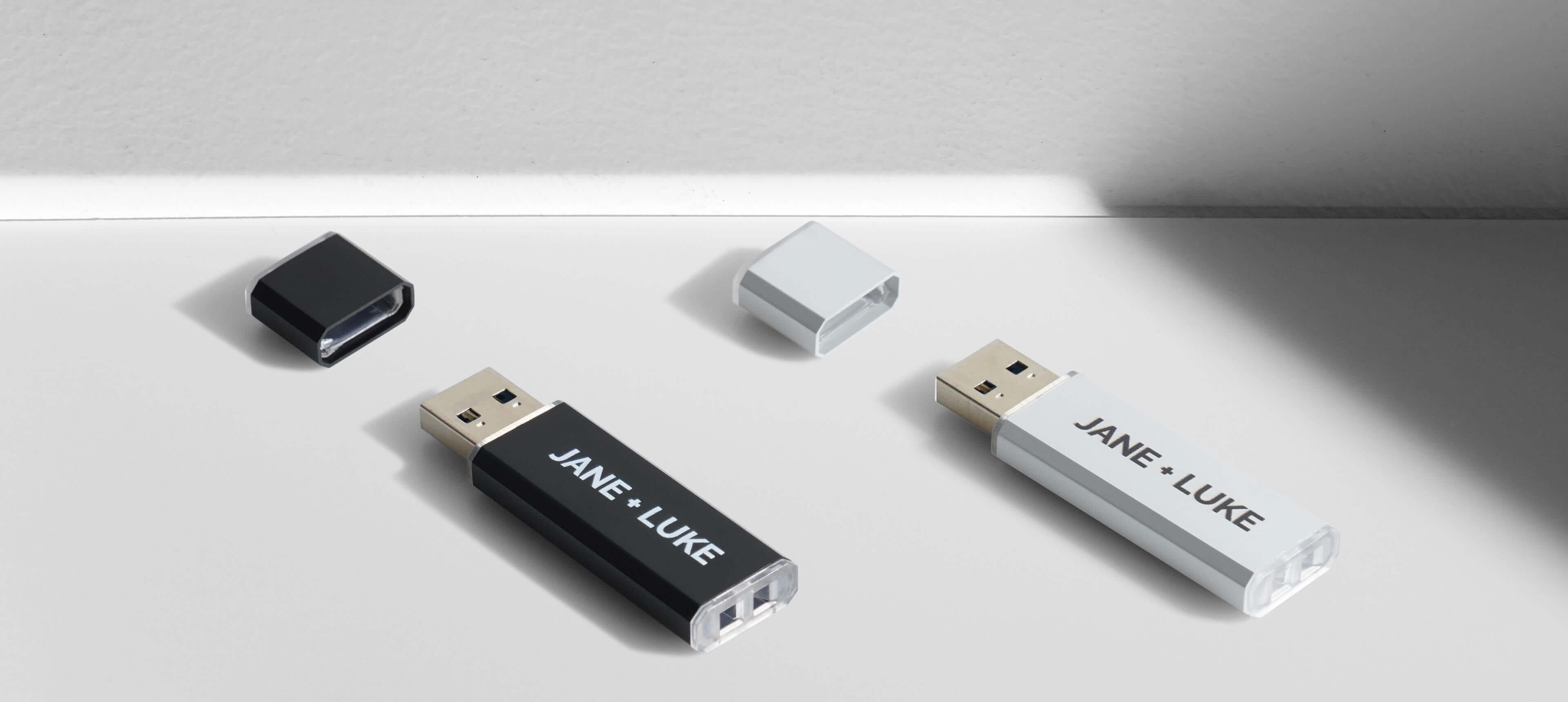 two metal usb drives in different colors on a white table