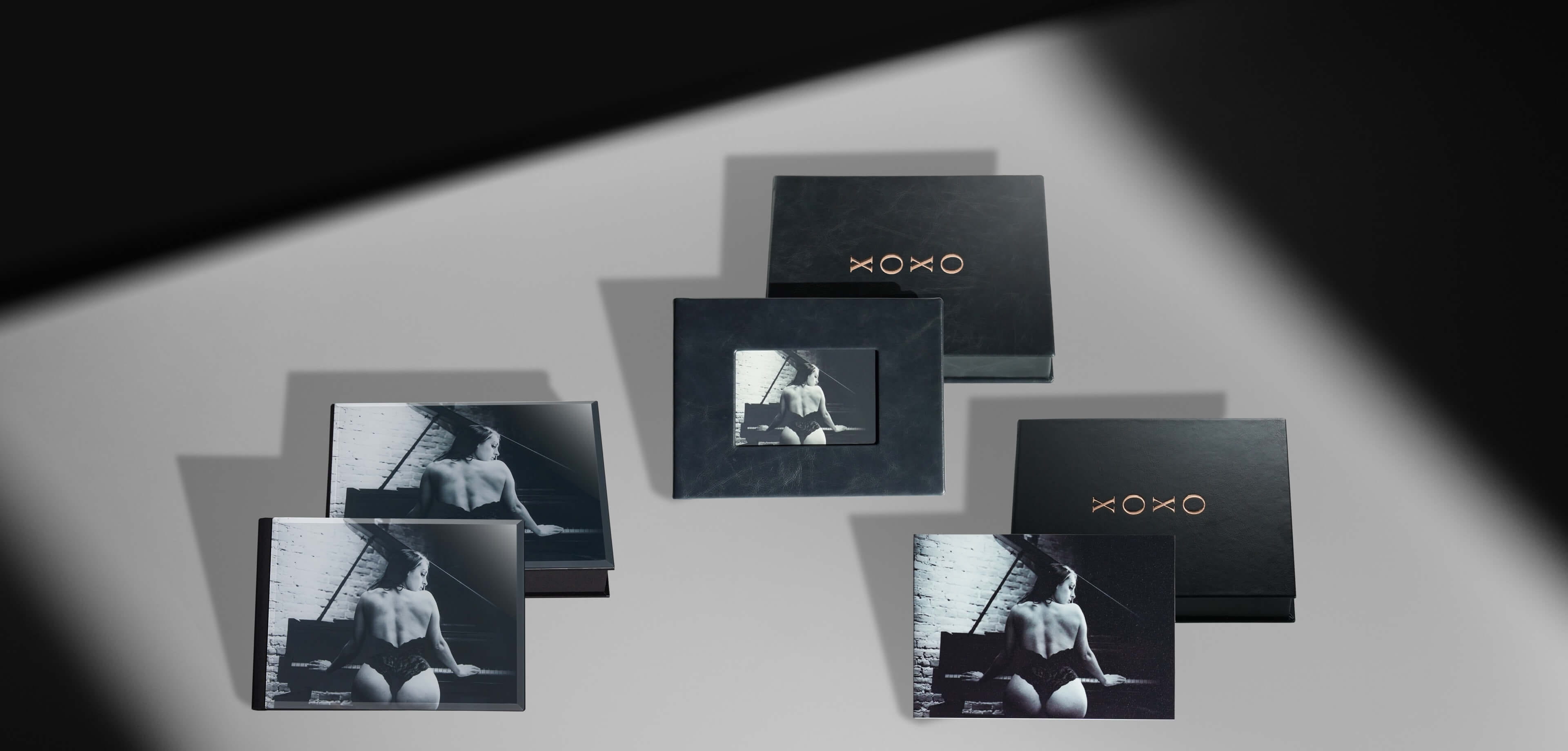 three presentation boxes with album leaning against them showing woman in lingerie beside a piano