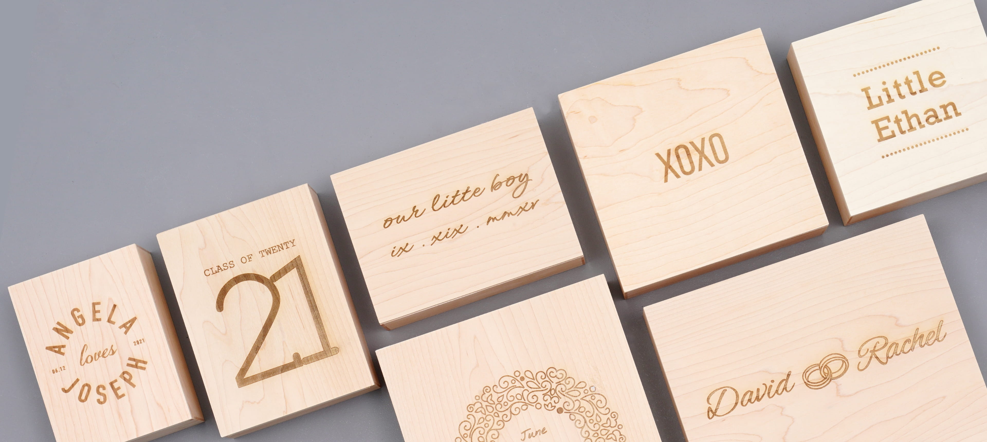 seven wood boxes with different engraving designs on a grey background