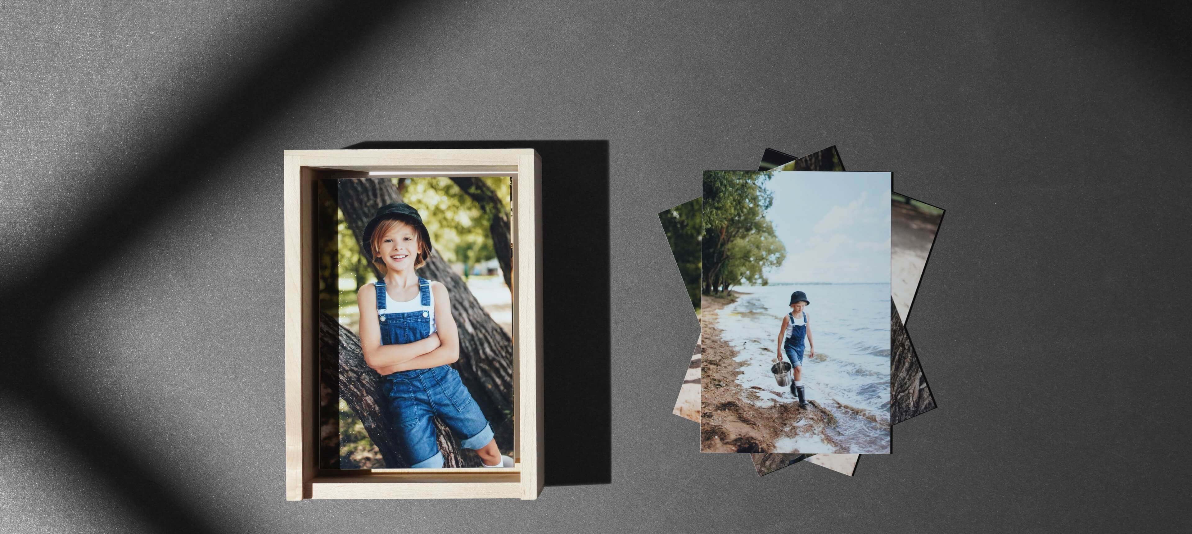 a wood box set showing prints of a boy inside next to a stack of photo prints