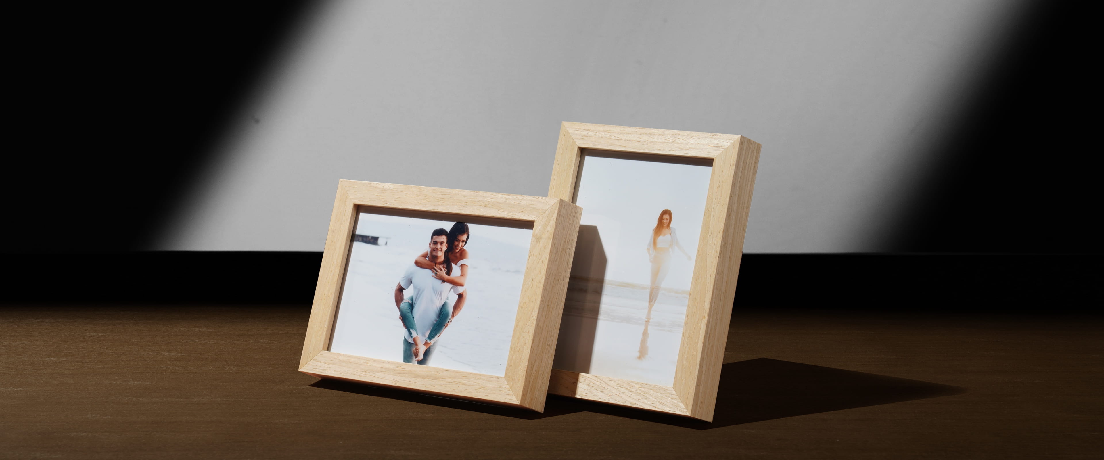 two framed tabletop wood prints on wood table showing a couple on the beach